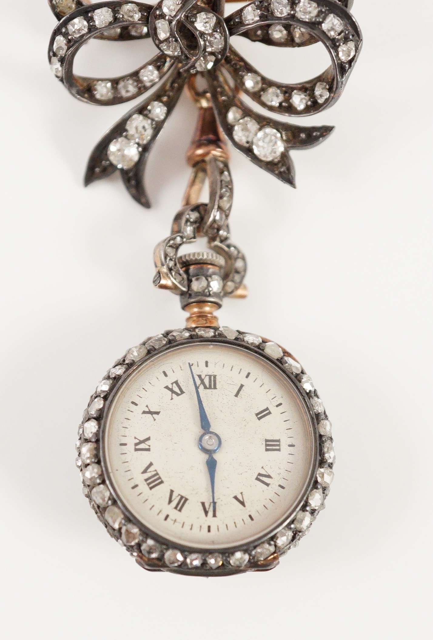 A late 19th century/early 20th century French 18ct gold and rose cut diamond encrusted fob lapel watch, on a rose cut diamond set ribbon bow suspension brooch
